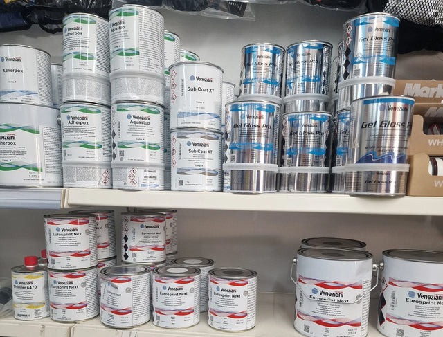 Scaffale delle vernici Veneziani in negozio: primer Adherpox e Aquastop, stucco Sub Coat XT, smalto Gel Gloss Pro