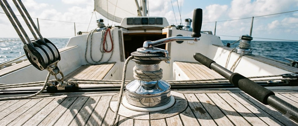 Composizione tecnica vela: un winch self-tailing, una maniglia per winch, un bozzello triplo e uno stick per timone su coperta in teak.