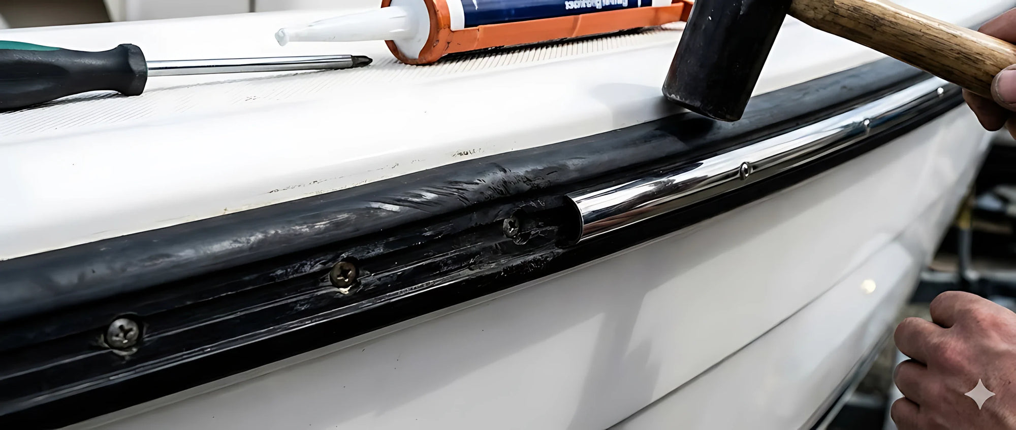 Dettaglio macro di un profilo bottazzo installato su scafo bianco: base in gomma nera con un inserto centrale in acciaio inox lucido e terminale di chiusura.