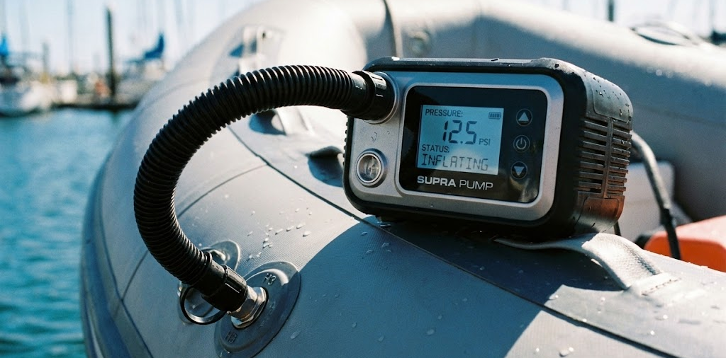 Gonfiatore elettrico digitale collegato alla valvola di un gommone grigio durante il gonfiaggio.