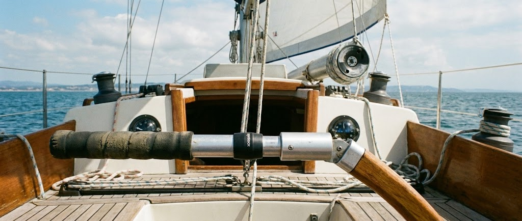 Uno stick del timone telescopico montato sulla barra, con sullo sfondo la prua della barca che mostra il tamburo dell'avvolgifiocco.