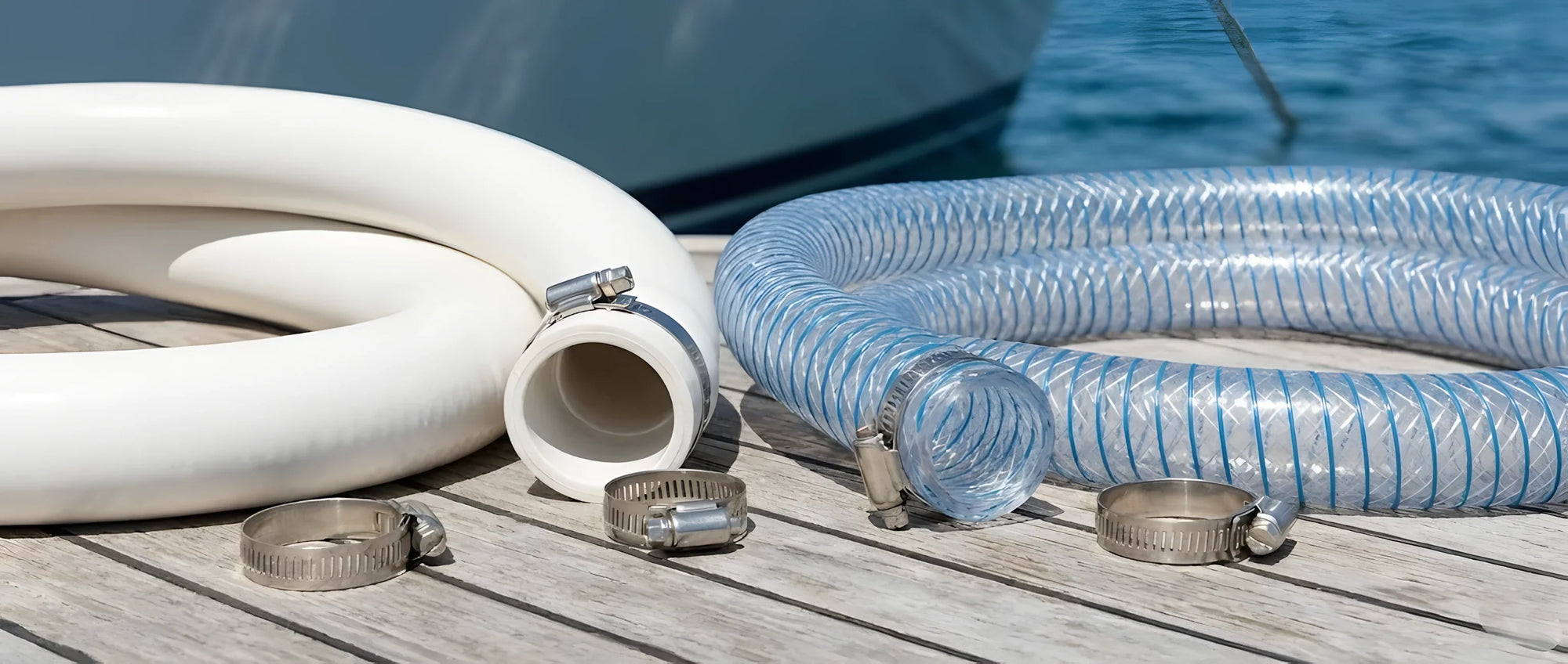 Diversi spezzoni di tubo (uno bianco spiralato, uno trasparente retinato) con due fascette in acciaio inox lucido pronte per il serraggio.