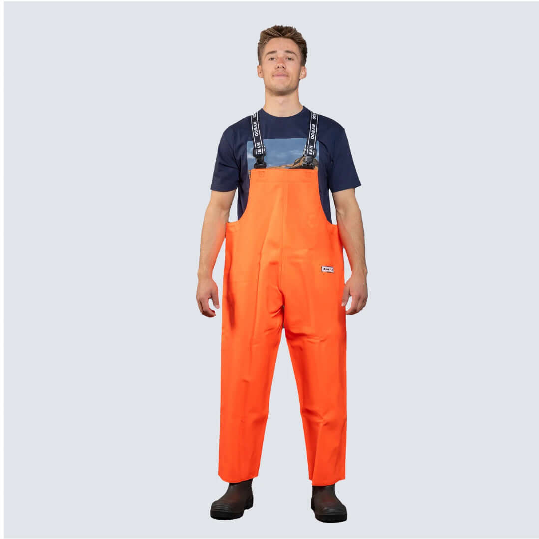 Salopette nautica OCEAN® arancione con bretelle nere, indossata su t-shirt navy, impermeabile da lavoro | Onautica