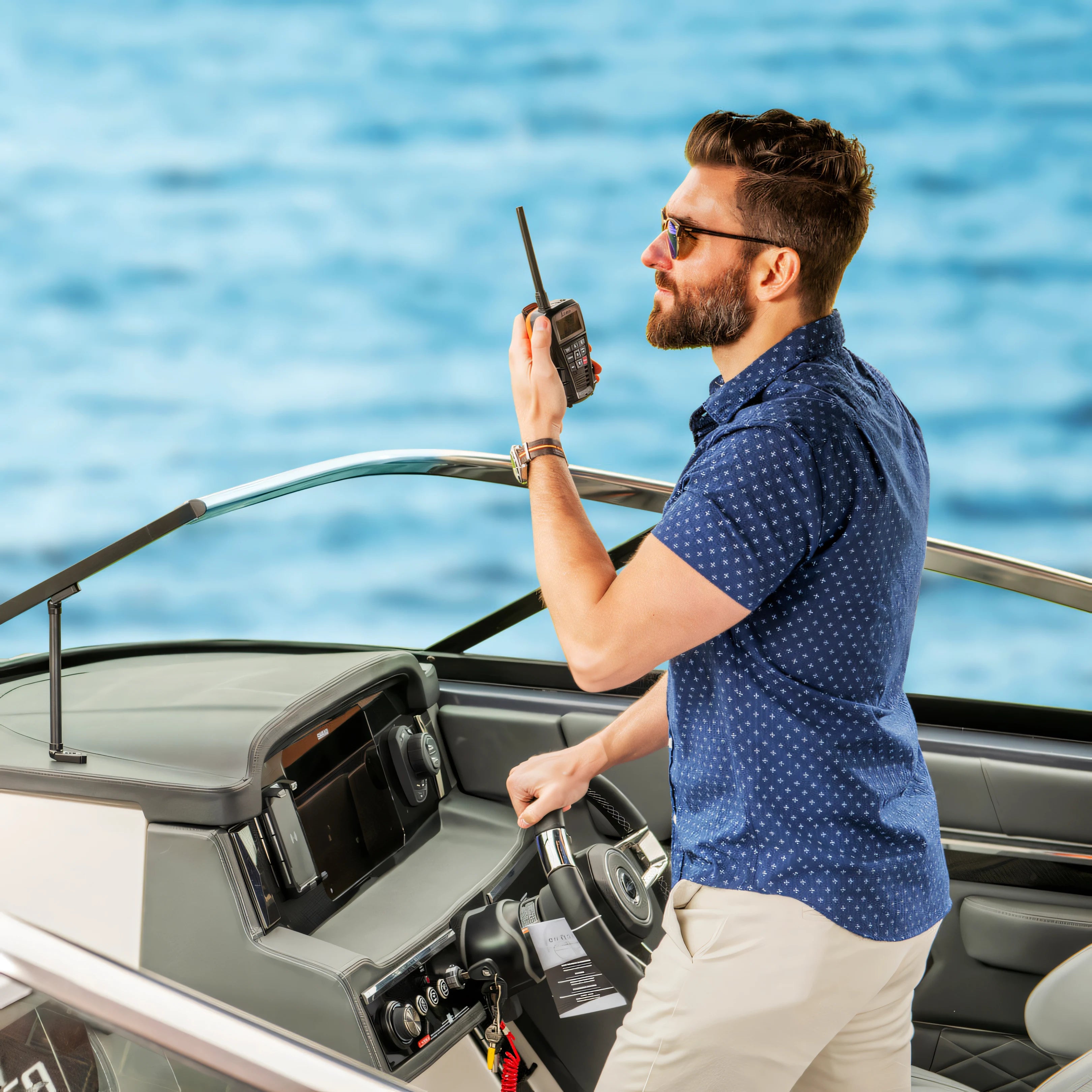 Diportista che chiama al VHF portatile Cobra BlueBound 150E nero alla console di guida | Onautica