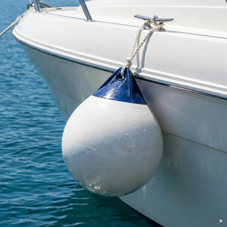 Parabordo sferico Heavy Duty corpo bianco testa blu appeso con cima alla murata di una barca sul mare | Onautica